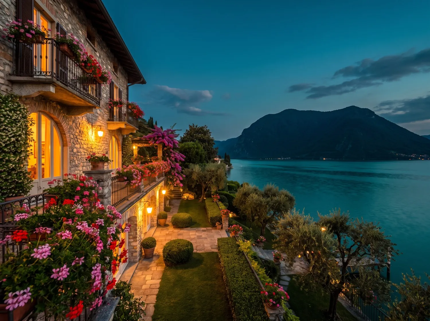 Casa in pietra con balconi fioriti e giardino curato affacciata sul Lago d'Iseo al tramonto (immagine illustrativa)