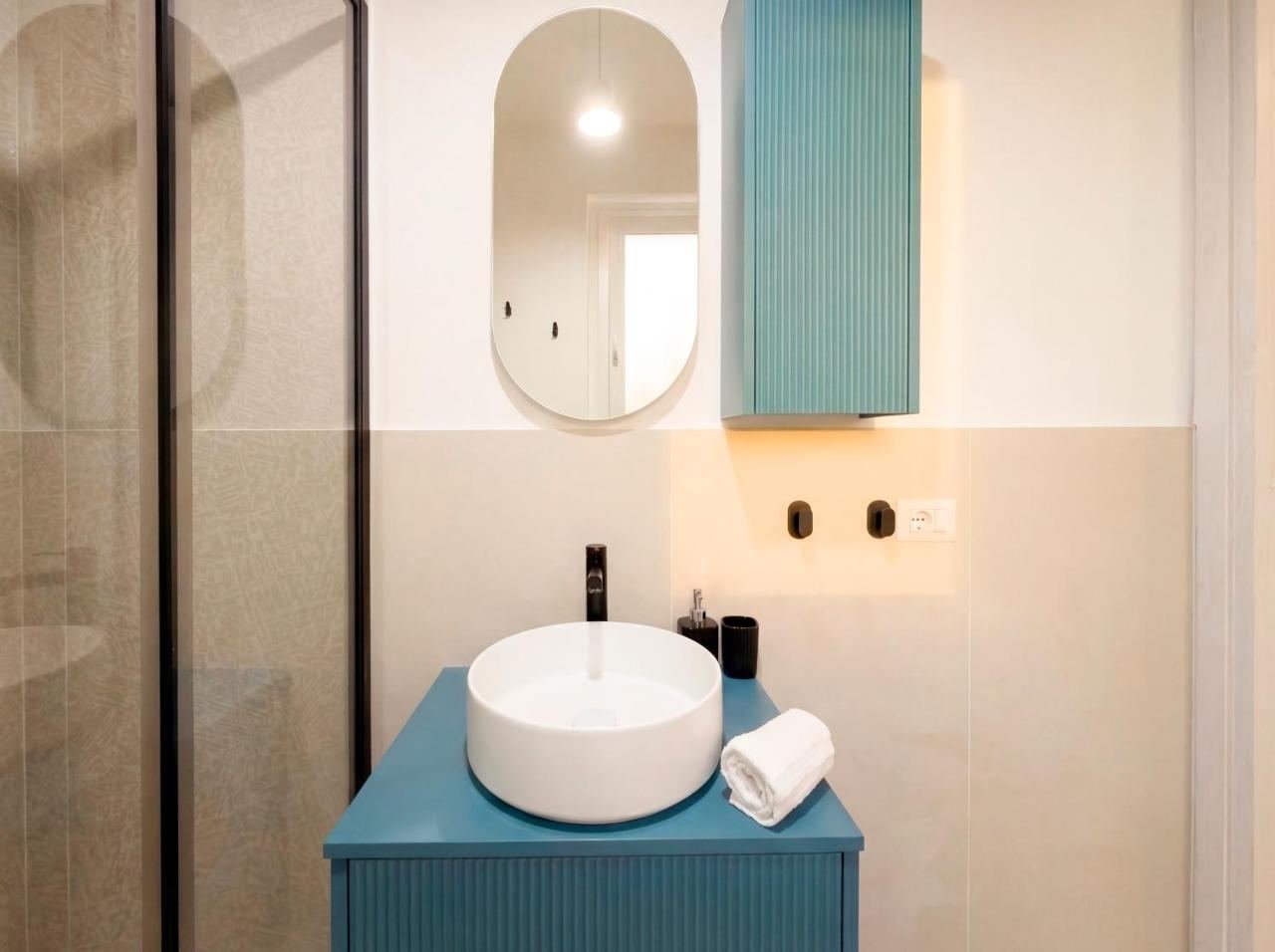 Bagno con doccia walk-in, lavabo tondo e mobile turchese