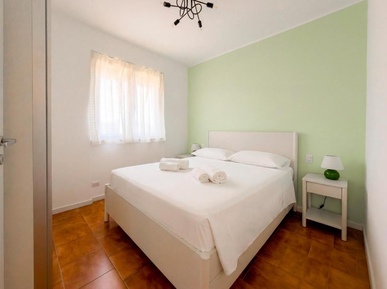 Camera da letto matrimoniale con parete verde salvia e biancheria fresca