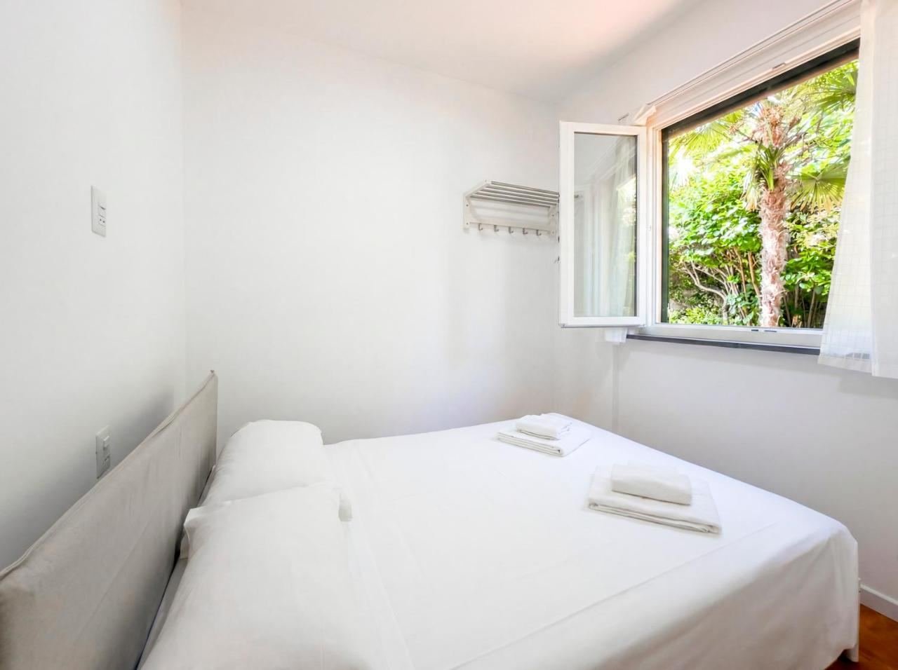 Seconda camera da letto luminosa con finestra affacciata sul giardino con palme