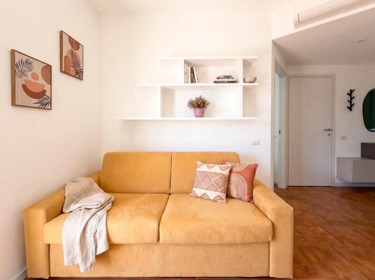 Angolo salotto del soggiorno con divano letto, mensole e cuscini decorativi