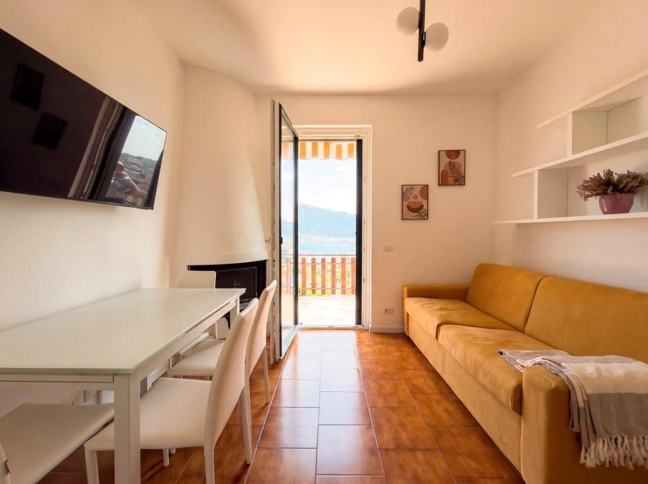 Soggiorno con divano e porta-finestra che si apre sulla terrazza con scorcio sul Lago d'Iseo