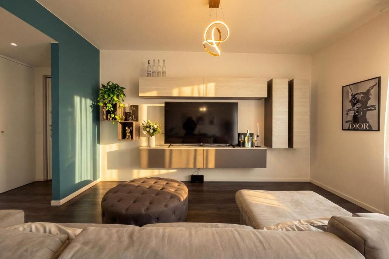 Sitzecke mit Smart-TV, Sitzpouf und petrolfarbener Wand
