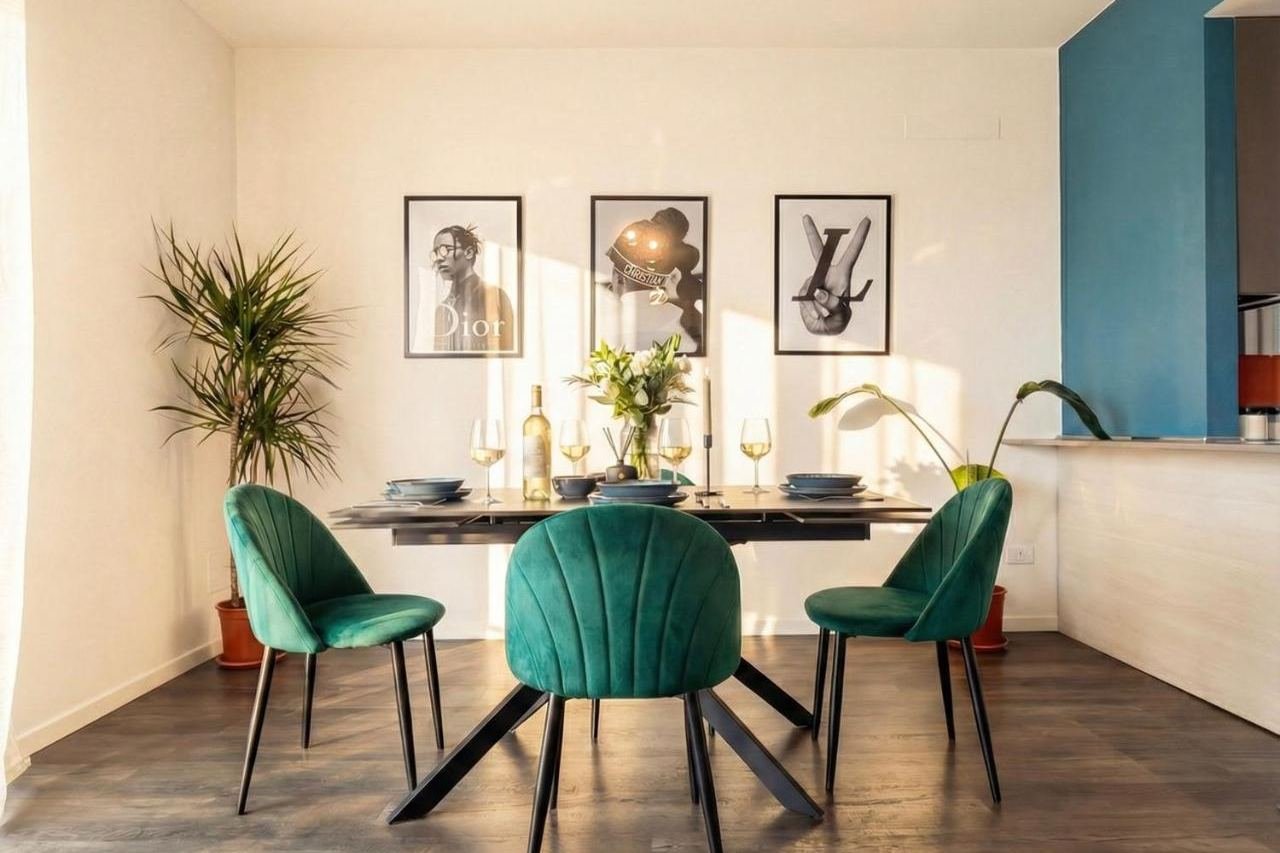 Design-Essbereich mit grünen Samtstühlen, Pflanzen und Bildern an den Wänden