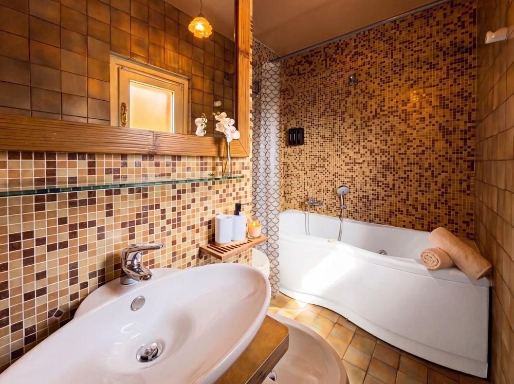 Bad im Dachgeschoss mit Whirlpool-Badewanne und goldenem Mosaik