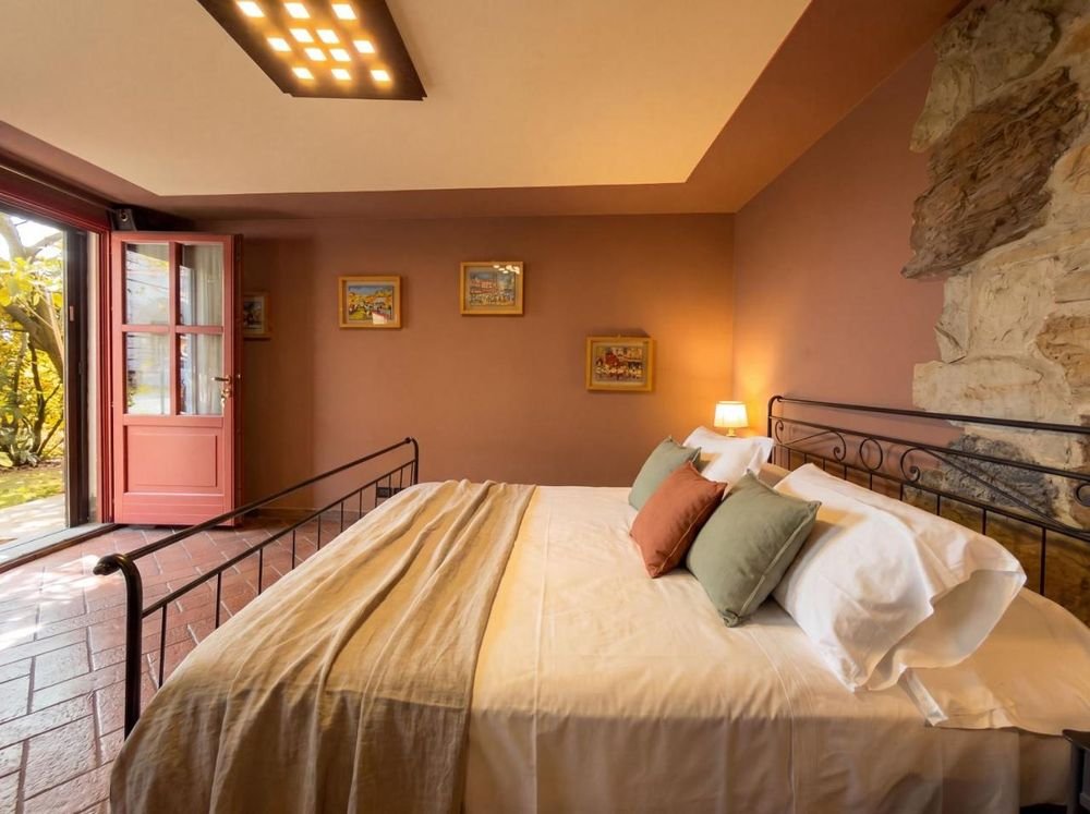 Schlafzimmer im Erdgeschoss mit schmiedeeisernem Bett und roter Tür zum Garten