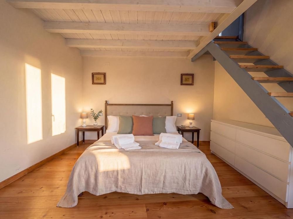 Doppelzimmer im Dachgeschoss mit weißen Sichtbalken und Treppe zum Zwischengeschoss