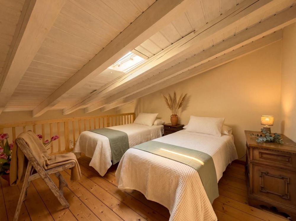 Zweites Zimmer im Dachgeschoss mit zwei Einzelbetten unter dem Holzdach