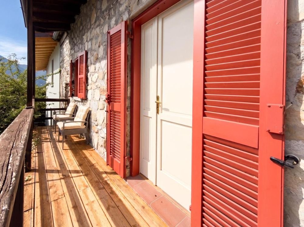 Holz-Loggia mit roten Fensterläden und offenem Talblick