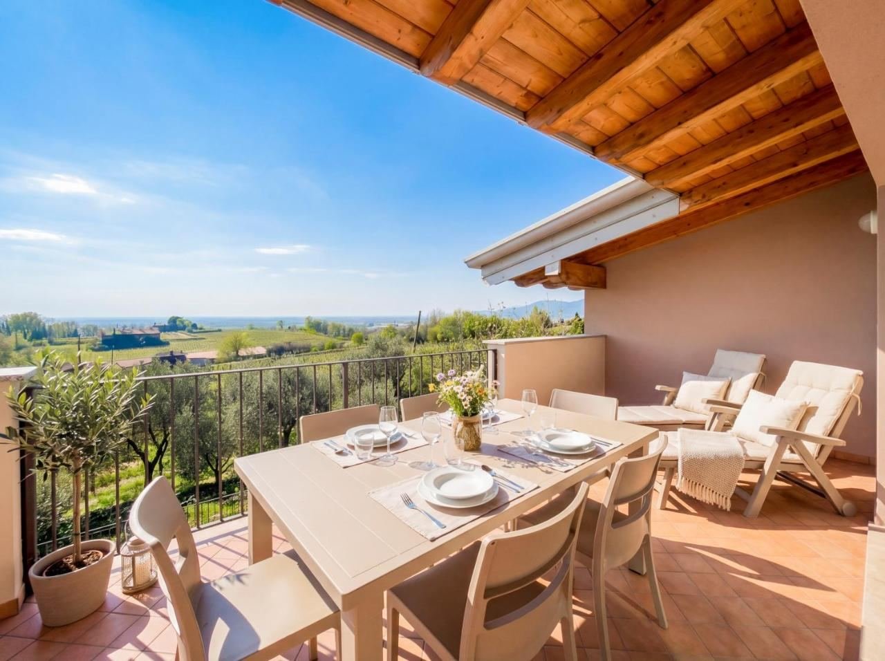 Private terrace of the loft with a table and a view over the hills and vineyards of Franciacorta in Adro