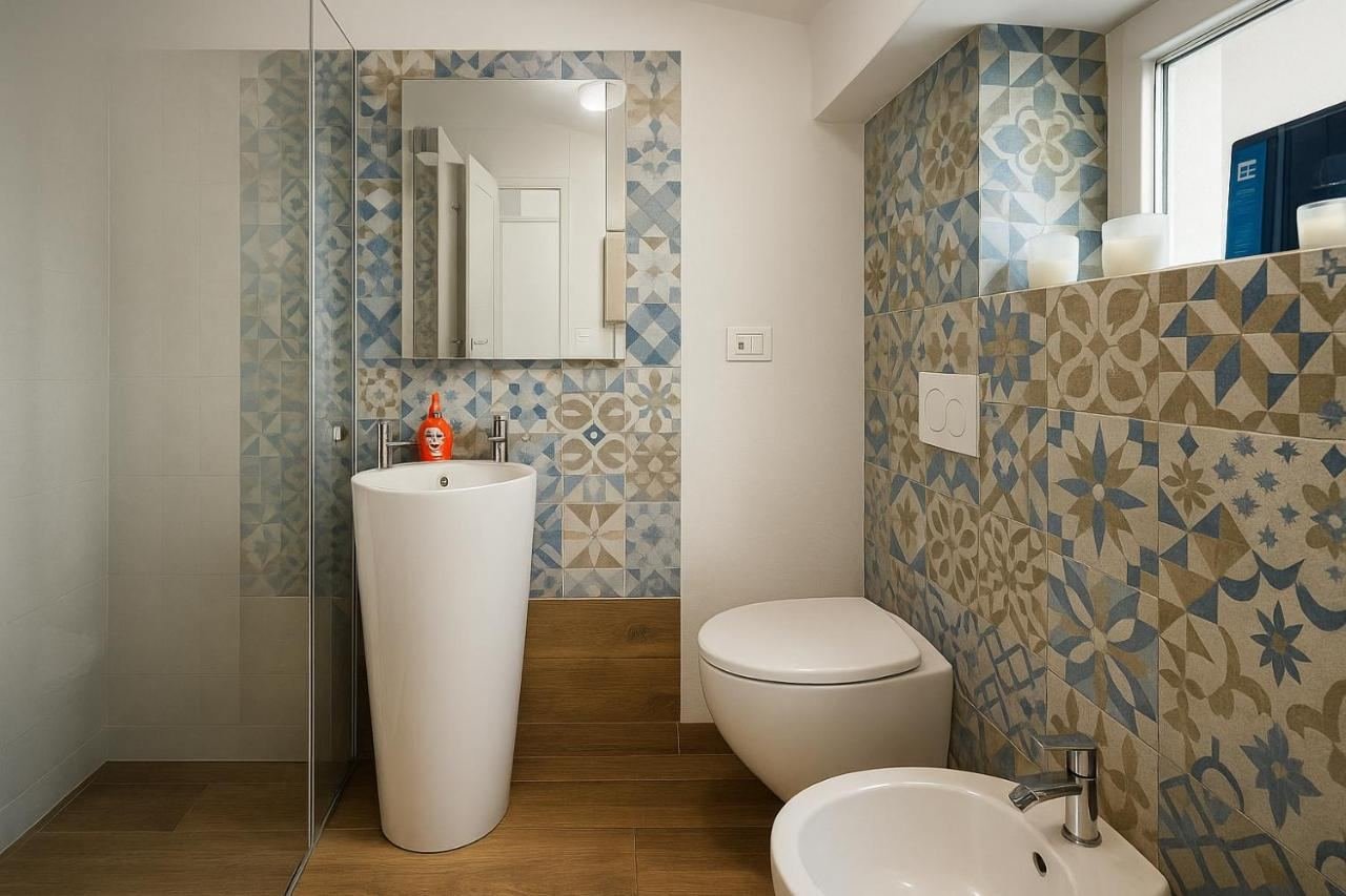 Bagno con doccia walk-in, lavabo a colonna e piastrelle decorate in azzurro