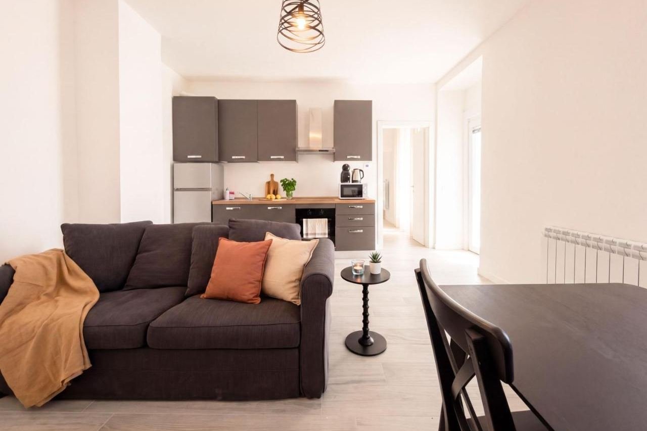 Open-plan living room of the Deluxe apartment with sofa and fitted kitchen