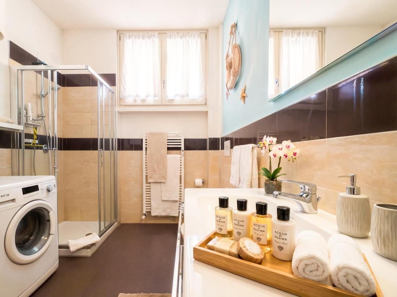 Badezimmer mit Duschkabine und Waschmaschine, helle Fliesen