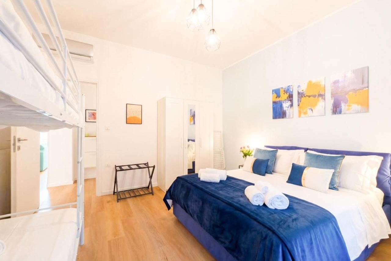 Helles Schlafzimmer mit blauem Doppelbett und Etagenbett