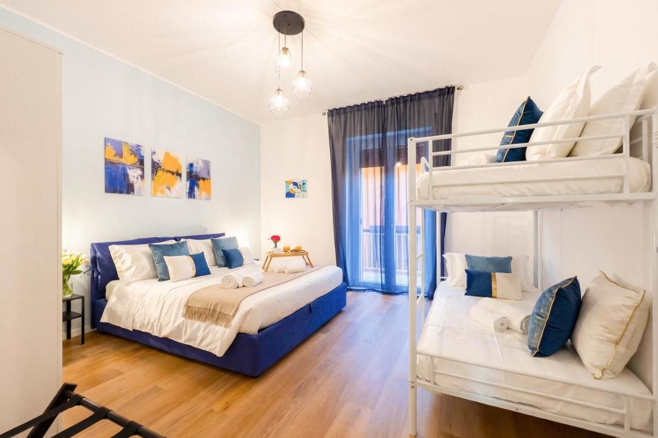Schlafzimmer mit Doppelbett und Etagenbett und Fenstertür zum Balkon