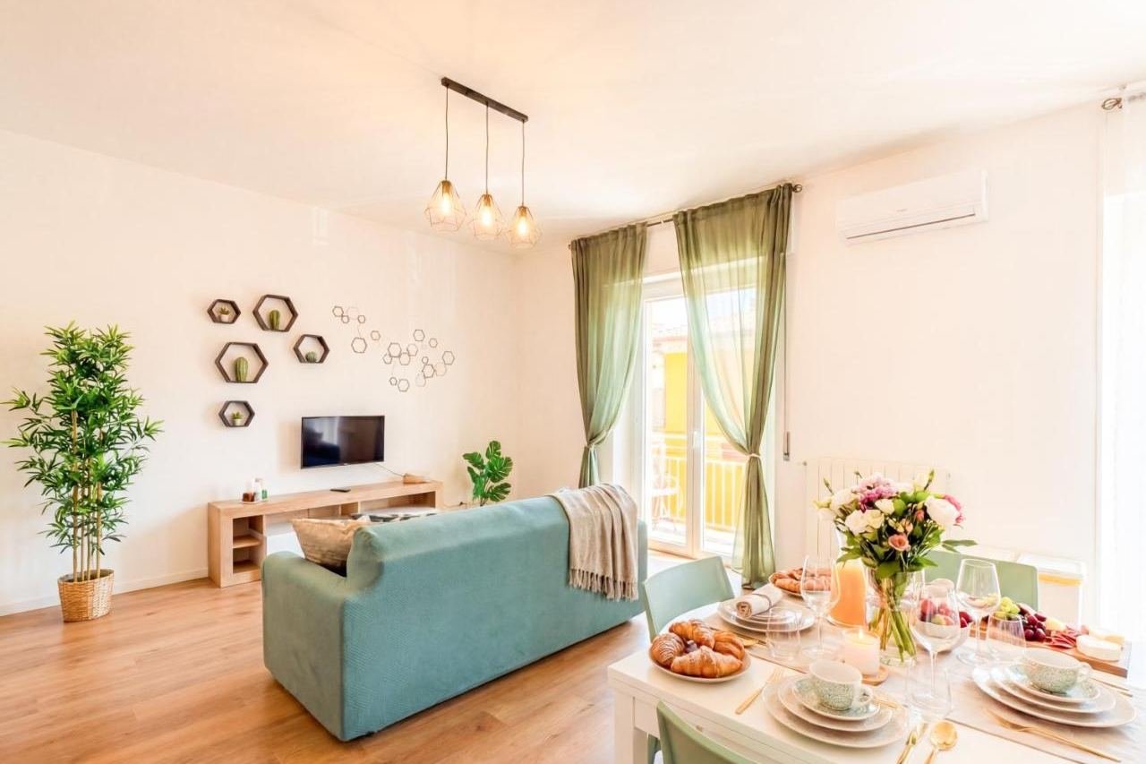 Wohnbereich mit salbeigrünem Sofa, Pflanzen und Essbereich