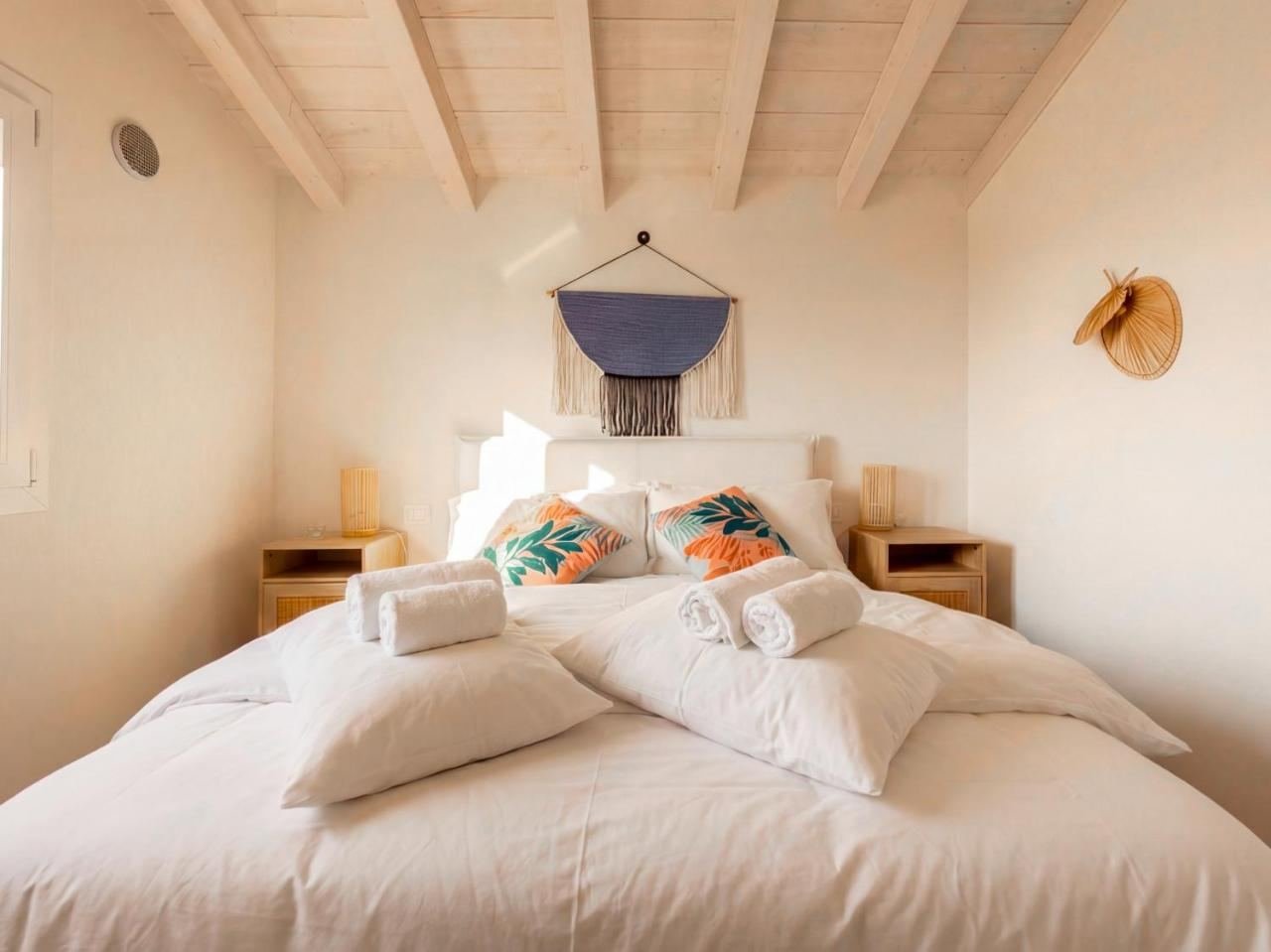 Bedroom with a double bed and a macramé headboard, under the exposed beams