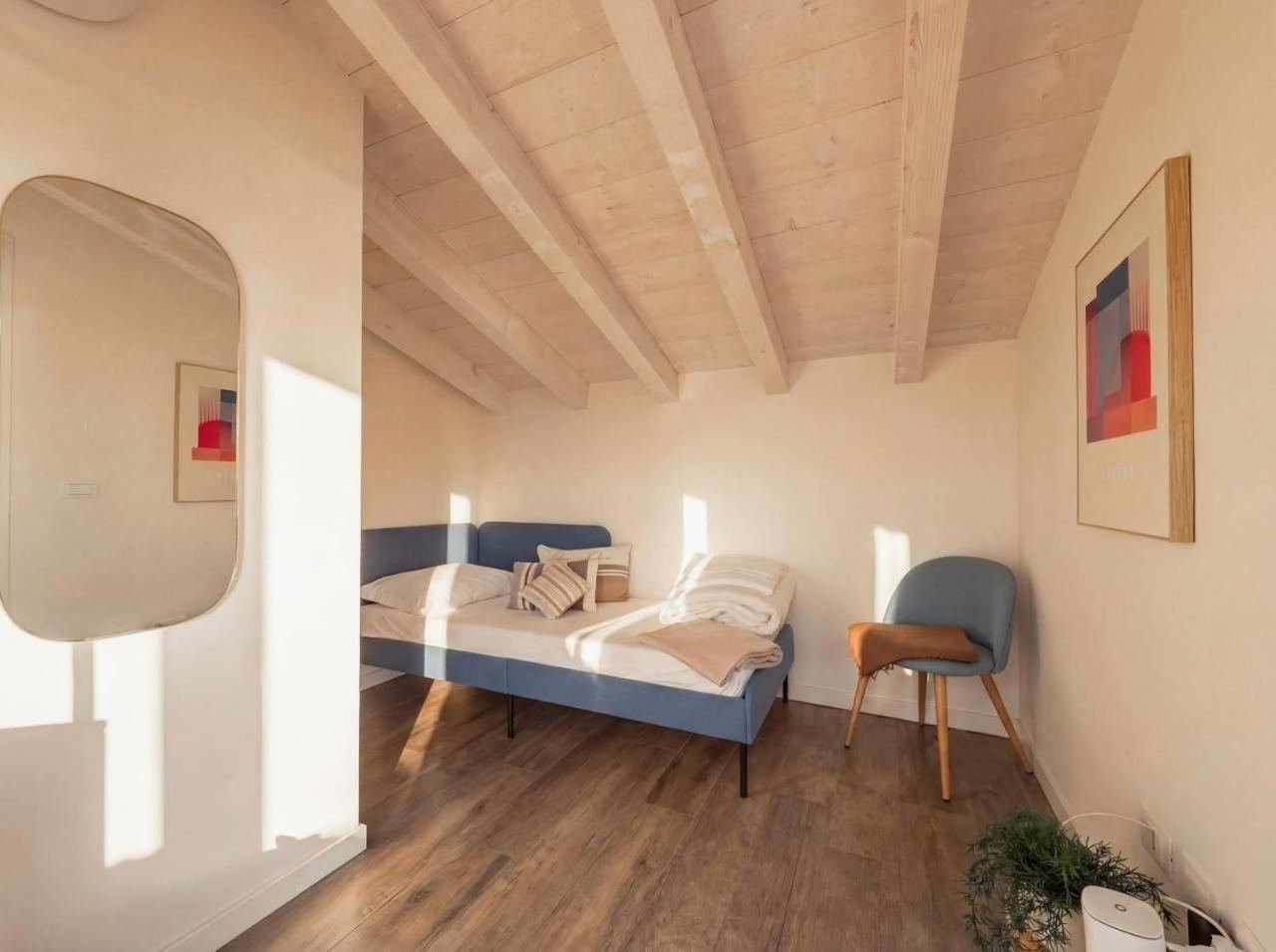 Bedroom with a blue single bed and wooden floors, bright